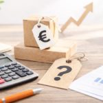 Càlcul del preu de serveis i productes amb calculadora i etiquetes sobre una taula de treball.